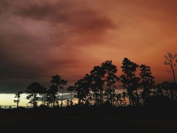 Silhouette of trees against cloudy sky