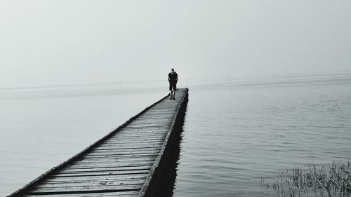 Rear view of man standing by sea against clear sky