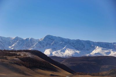 Scenic view of snowcapped mountains against clear blue sky