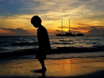 Silhouette man standing on beach against sky during sunset