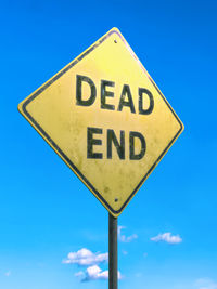 Low angle view of road sign against blue sky