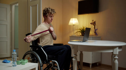 Young man exercising while sitting at home