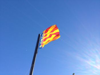 Low angle view of flags against clear blue sky