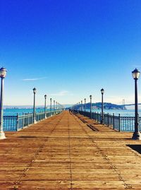 Pier on beach against clear blue sky