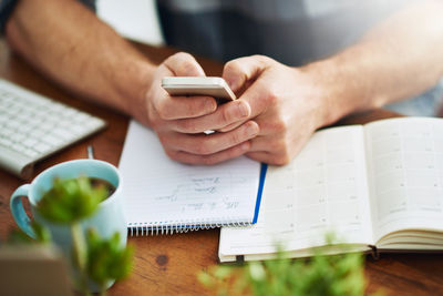 Midsection of woman using mobile phone at table