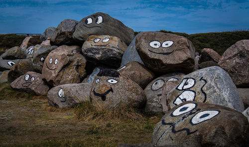 Text on rock on field against sky