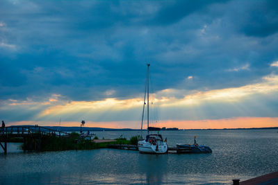 Sailboats in sea against cloudy sky