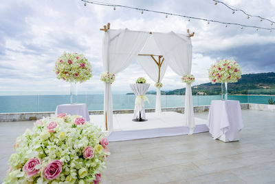 Flower pots on table by sea against sky