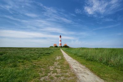 Lighthouse on field against sky