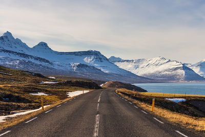 Road amidst snowcapped mountains against sky