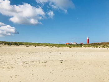 Lighthouse on beach against sky