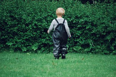 Rear view of boy walking on grass at park