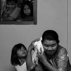 Children looking at grandmother holding wrapped fabric on neck