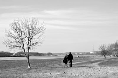 Rear view of people walking on snow covered landscape