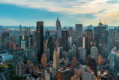 Aerial view of city buildings against cloudy sky