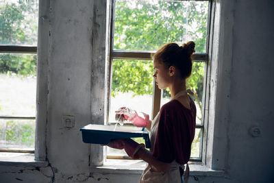 Side view of woman using digital tablet while standing in front of house
