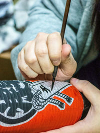 Close-up of woman painting on lantern