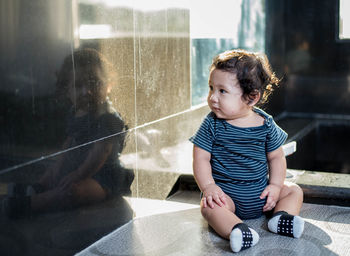 Cute boy sitting in glass window