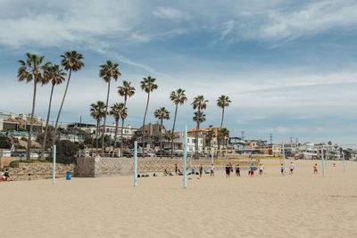 Group of people playing beach volleyball against sky