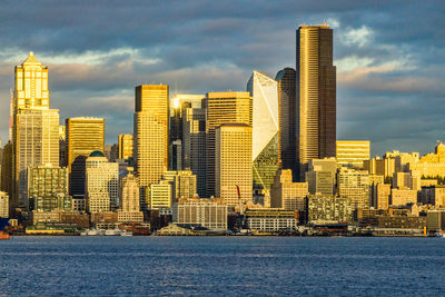 The setting sun makes a section of the city of seattle shine across elliott bay.