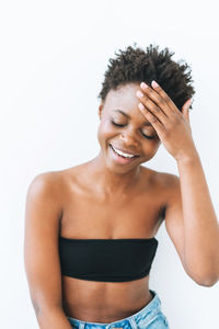 Portrait of smiling beautiful young african american woman in black top isolated on white background