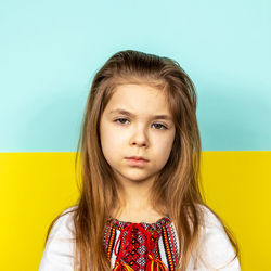 A sad girl in an embroidered shirt on the background of the ukrainian flag.