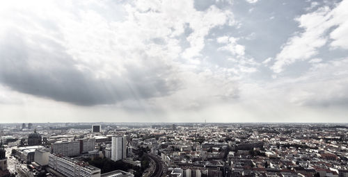 Aerial view of cityscape against cloudy sky