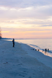 Silhouette man on beach against sky during sunset