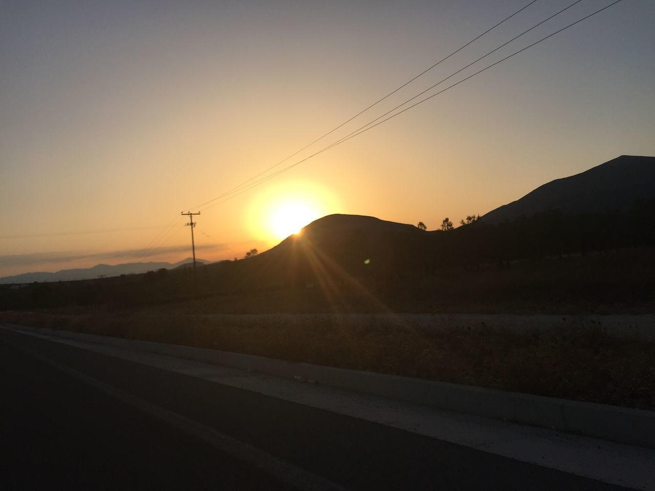 EMPTY ROAD LEADING TOWARDS MOUNTAINS AT SUNSET