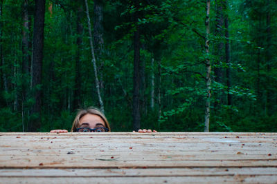 Portrait of woman hiding under tree in forest