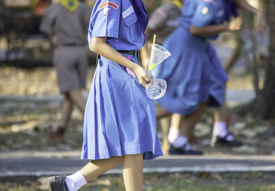 Midsection of schoolgirl holding disposable containers on footpath