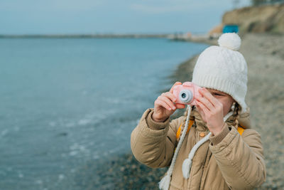 Rear view of woman wearing hat standing at beach