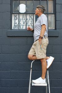 Side view of young man looking away against wall