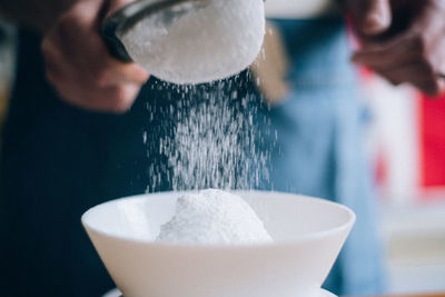 Midsection of person sifting flour 