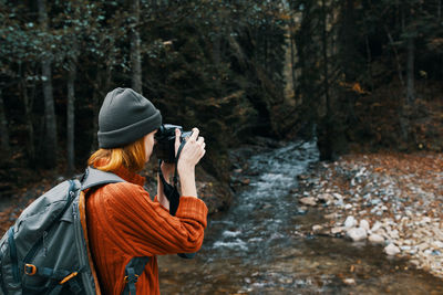Rear view of woman photographing in forest