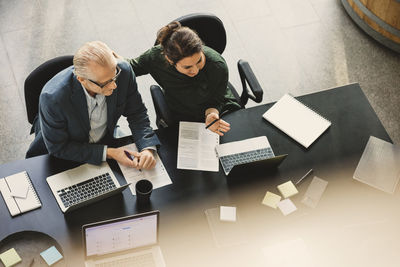 High angle view of businesswoman having discussion with colleague at table in office