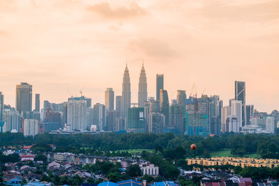 Modern buildings in city against sky during sunset