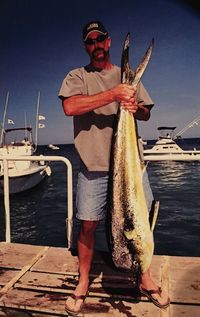 Full length of man holding fish in sea against sky