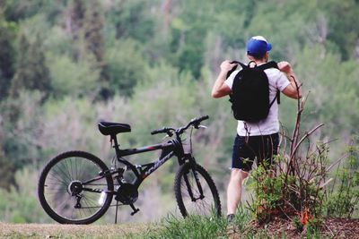 Rear view of man with bicycle standing on street