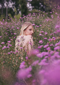 Portrait of woman standing by pink flowers on field