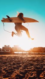 Low angle view of woman jumping on beach against sky