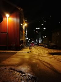 Empty road along illuminated street at night