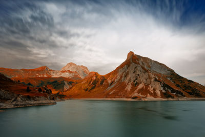 Scenic view of lake by snowcapped mountains against sky