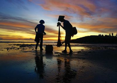 Silhouette of people on beach at sunset