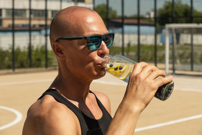 Side view of young man drinking wine in gym