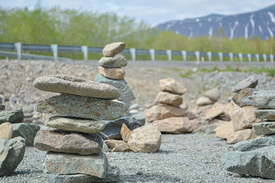 Stack of stones on field against sky