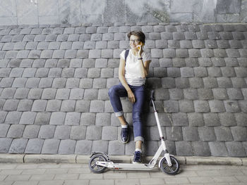 Smiling woman talks by smartphone after riding kick scooter. eco-friendly urban transport.