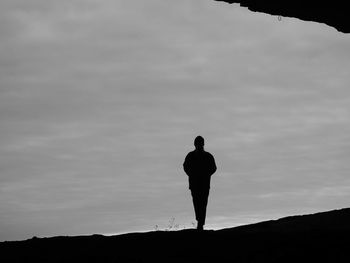 Rear view of silhouette man standing on mountain against sky