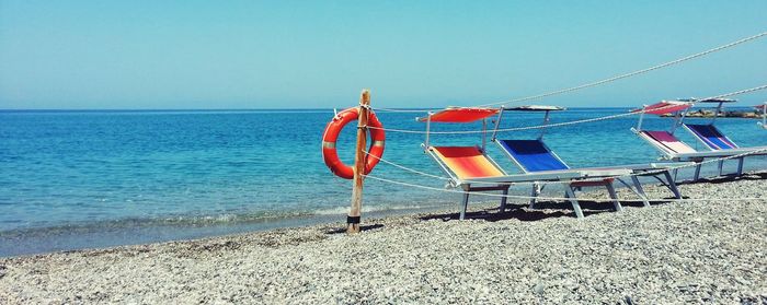 Deck chairs on beach against clear sky