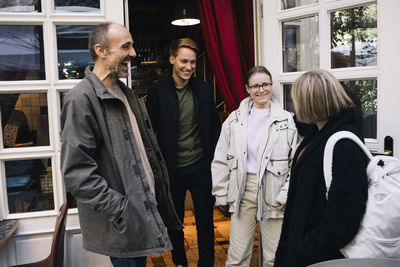 Happy family talking to each other while standing at restaurant doorway